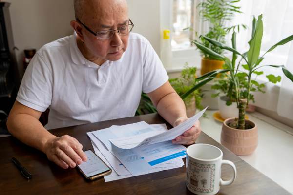 Man reading bills and using phone as calculator 