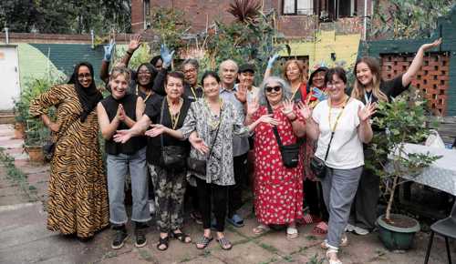 Group of people smile and hold their hands in the air