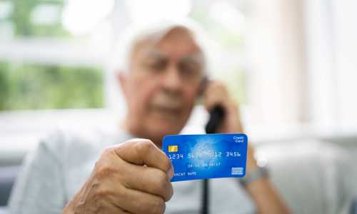 man holds his credit card to the camera