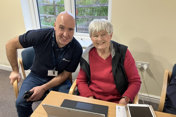 Resident and digital trainer smile in front of computer 