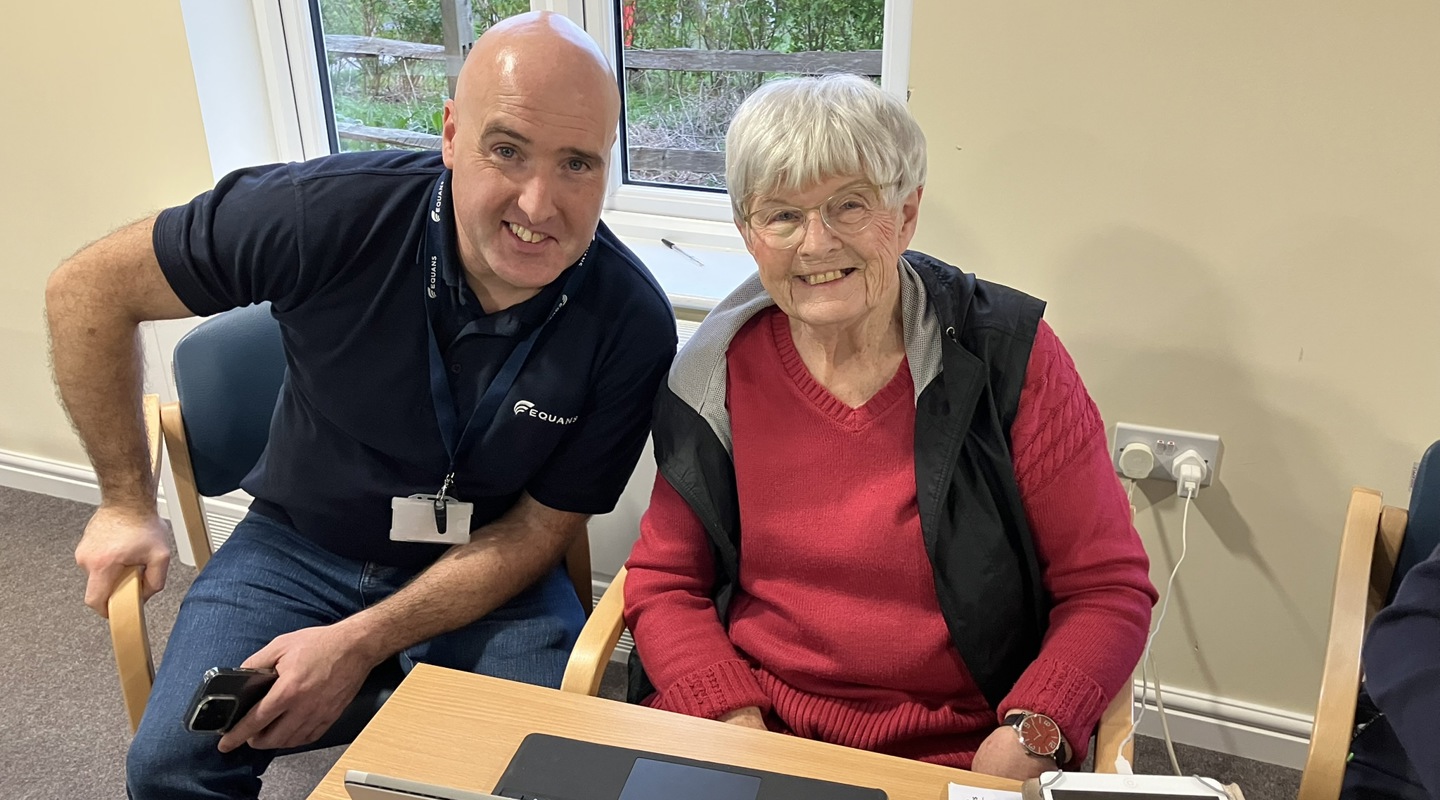 Resident and digital trainer smile in front of computer 