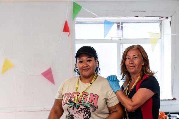 Two women stand next to a table at food giveaway 