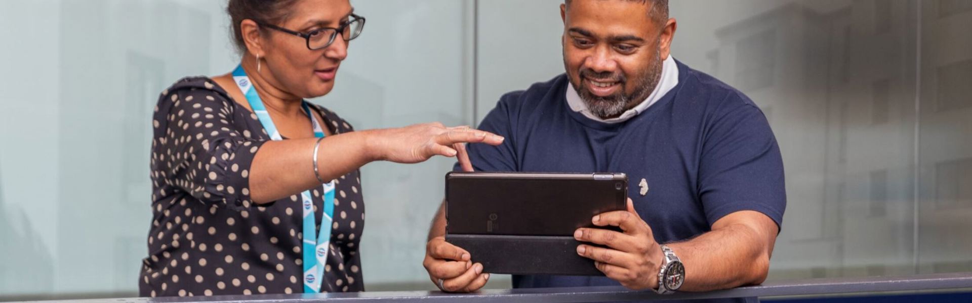 A man holds and ipad and a woman points at it