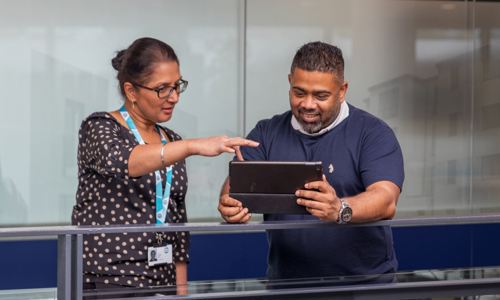 A man holds and ipad and a woman points at it