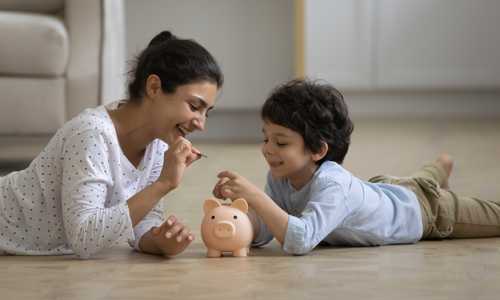 Mum and son put coins into a piggy bank