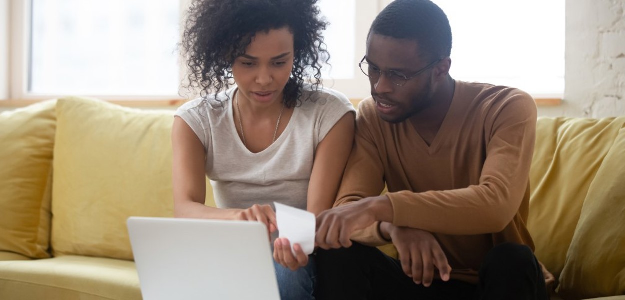 Couple look at a receipt in front of their laptop