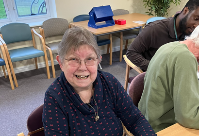 A resident smiles with a computer on the table in front of her