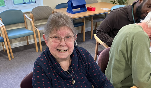 A resident smiles with a computer on the table in front of her