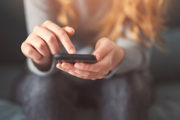 image: a woman looking at the Southern Housing website on her phone