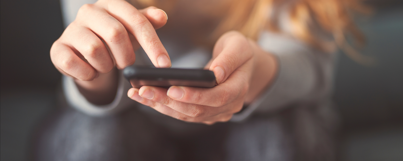 image: a woman looking at the Southern Housing website on her phone
